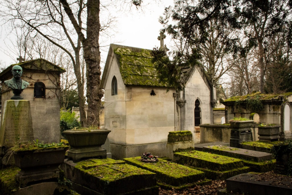graves with moss and trees in pere laschaise cemetery