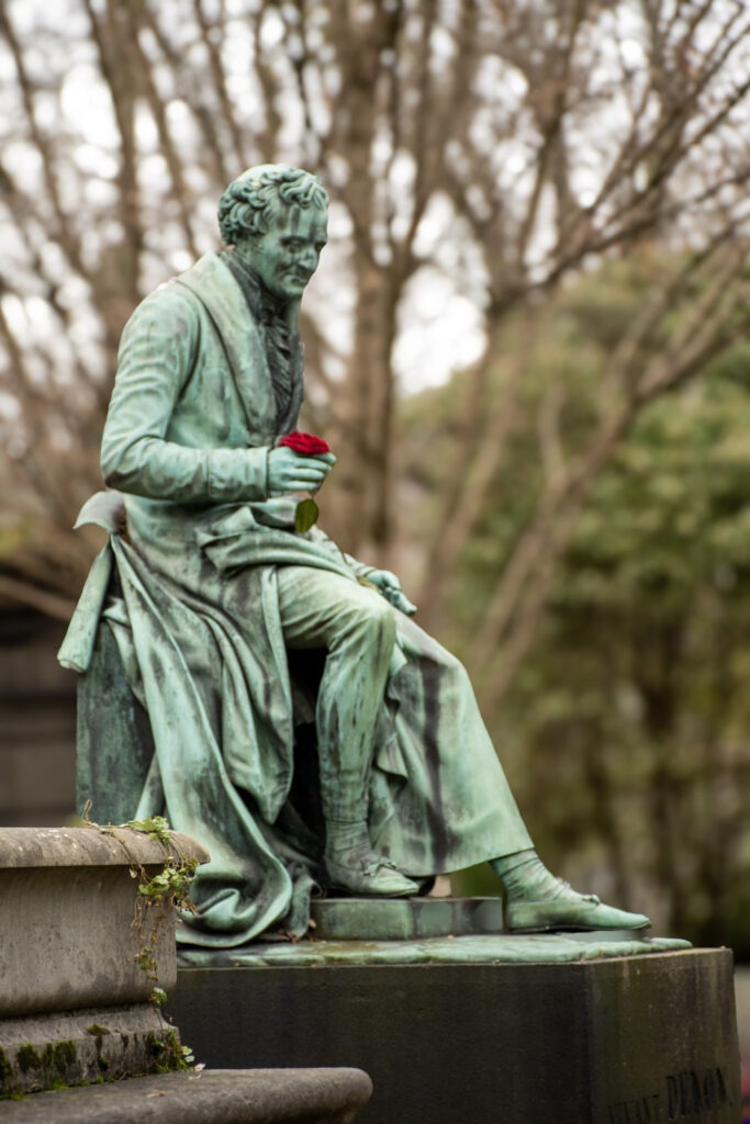 bronze statue of man holding a red rose on a pere lachaise visit in paris
