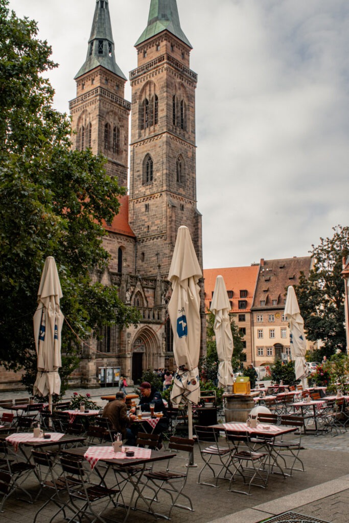 market square with tables and chairs with tall cathedral while spending one day in nuremberg