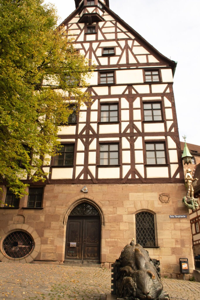 tall timber framed house with tree and a rabbit sculpture 