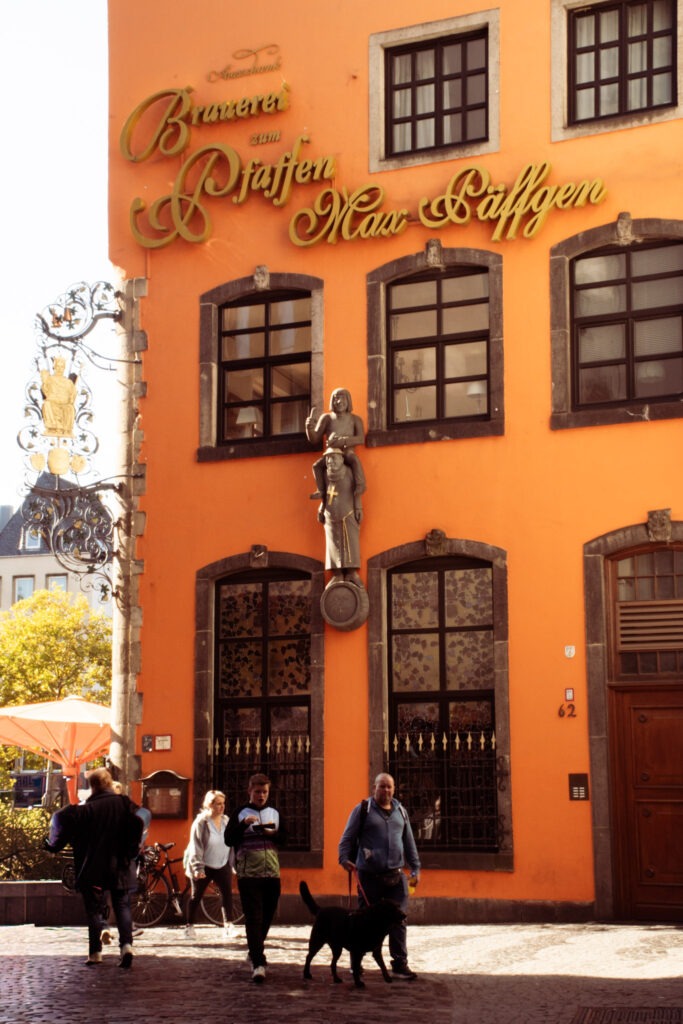 orange building with people walking on cobble stone street in Cologne Germany