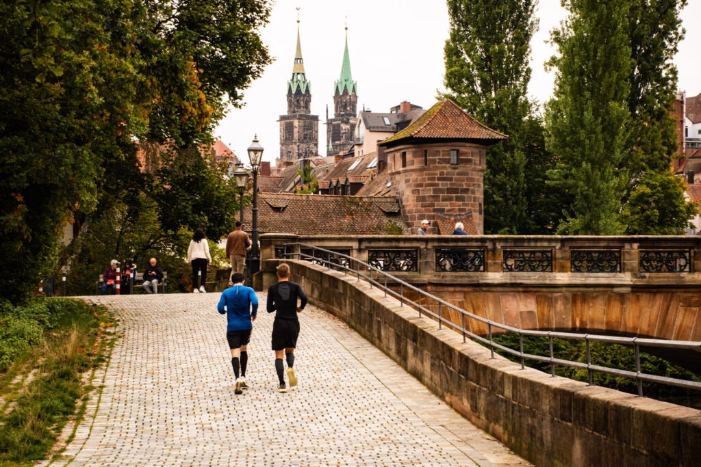 bridge with city tower and church with two men running in nuremberg