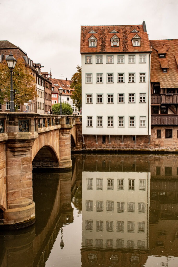 Top Nuremberg Attractions for Thoughtful Travellers 5 tall white building reflected in the water with famous bridge is one of the nuremberg attractions to visit