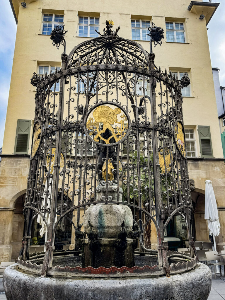 iron trellis fountain with pig in the centre with a farmer, this is considered one of Stuttgart attractions mostly connected to legends and German culture