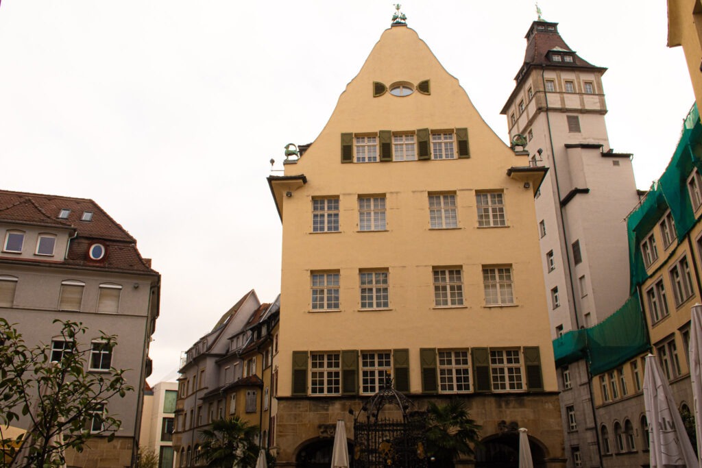 the older part of town with narrower streets showing a yellow building and clock tower considered one of the areas for tourist attractions in stuttgart
