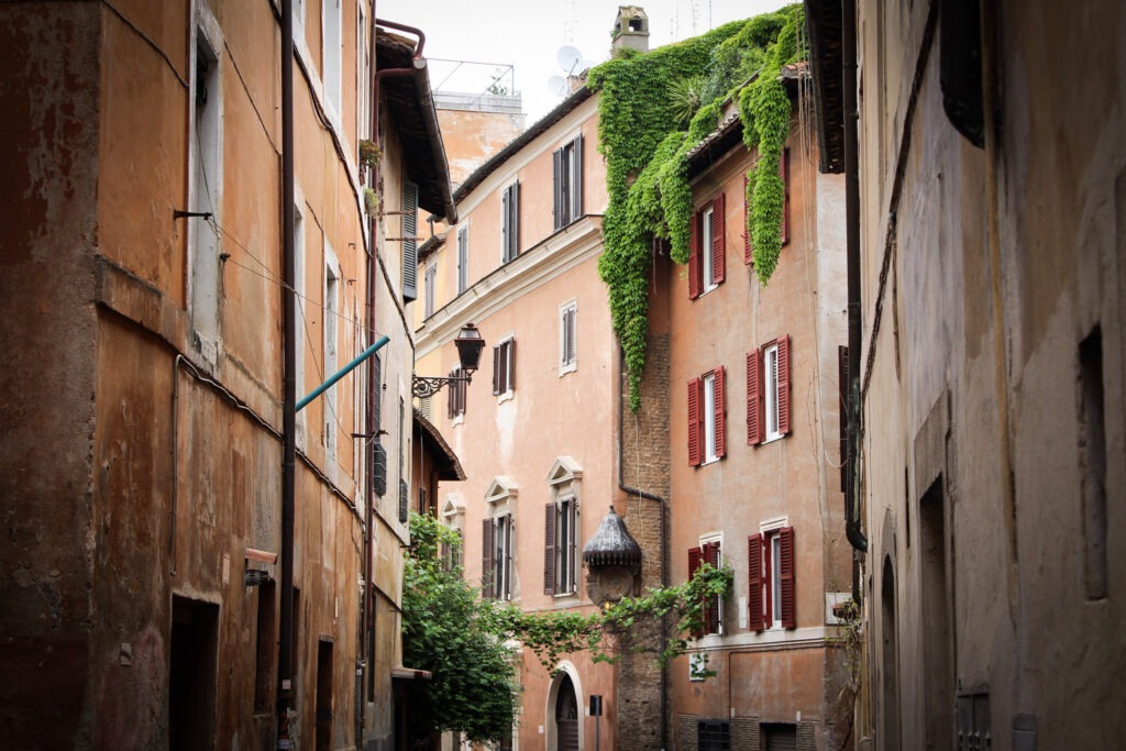 pink buildings with ivy growing on them in the trastevere neighbourhood of rome