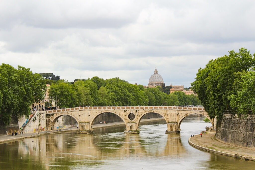 old bridge in Rome with st peter's dome on the sky with trees flanking each side while spending two days in rome
