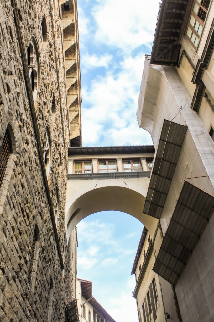 looking up between buildings in Florence seeing a bridge connecting two buildings