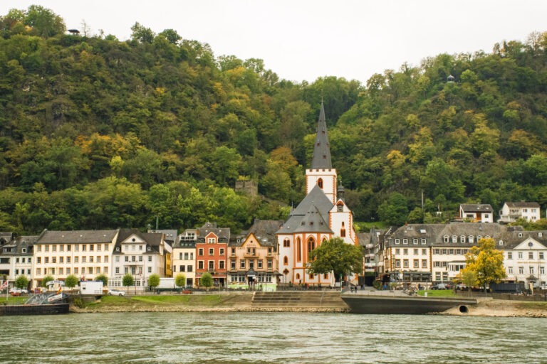 A Rhine River town with church steeple, ferry crossing on the Rhine with mountains