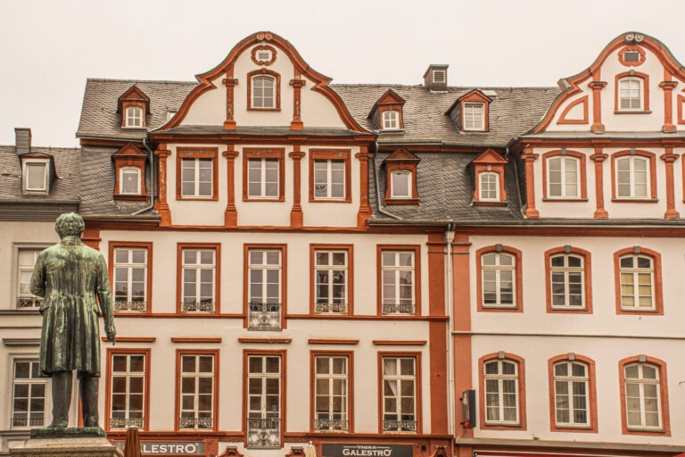 red and white baroque architecture in the old town with a bronze statue as one of the things to do in Koblenz