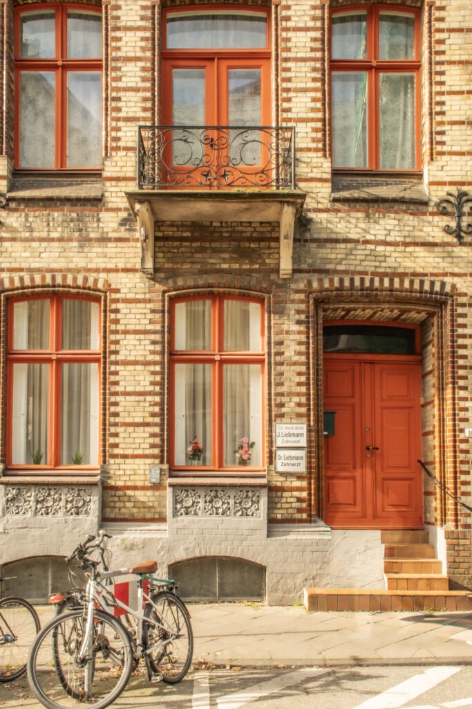 yellow brick with red door and trim on windows on a townhouse in lubeck germany with bikes