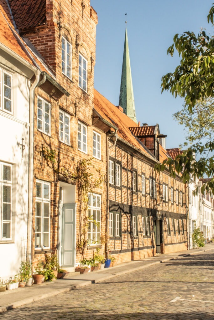 rows of town houses some in red brick facades others in white facing the river while visiting lubeck for the day