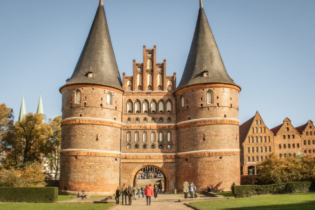 holsentar gate in while visiting lubeck in a reddish brown brick with two cylinder towers with blue sky and green grass