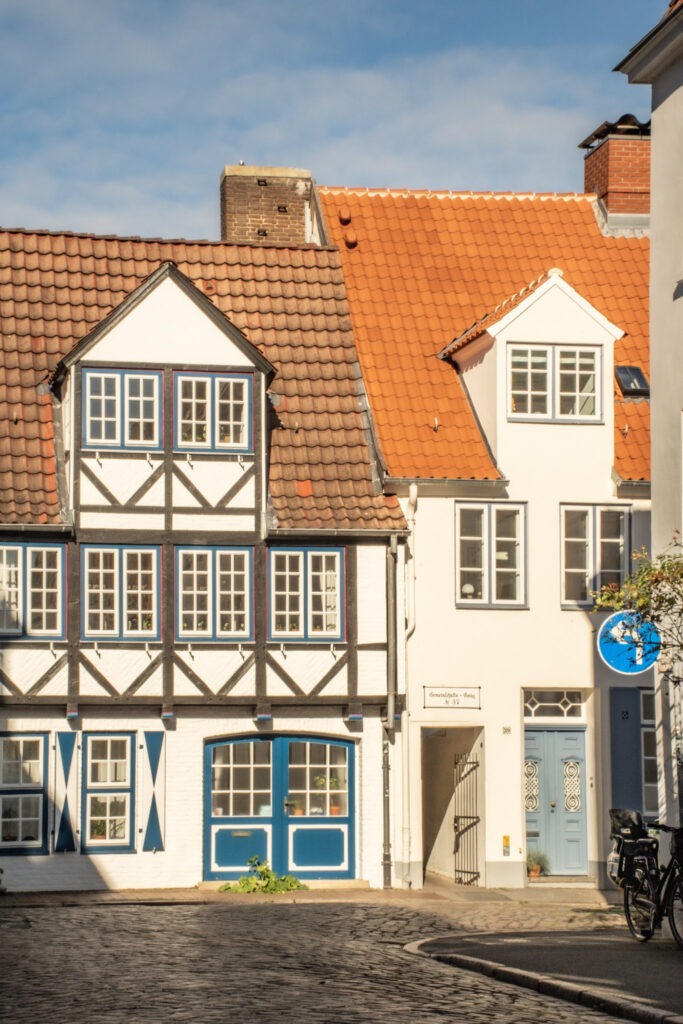 Visit Lubeck for its distinct architecture of sloped orange rooftops, white brick with gables and blue doors