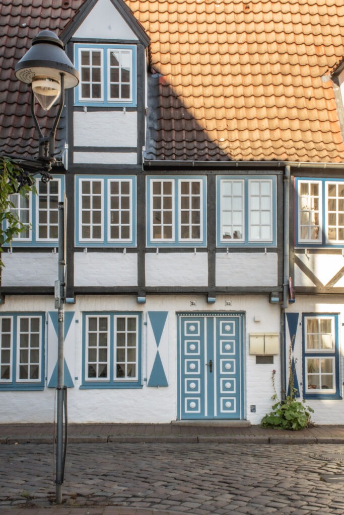 Visit Lubeck for its distinct architecture of sloped orange rooftops, white brick with gables and blue doors