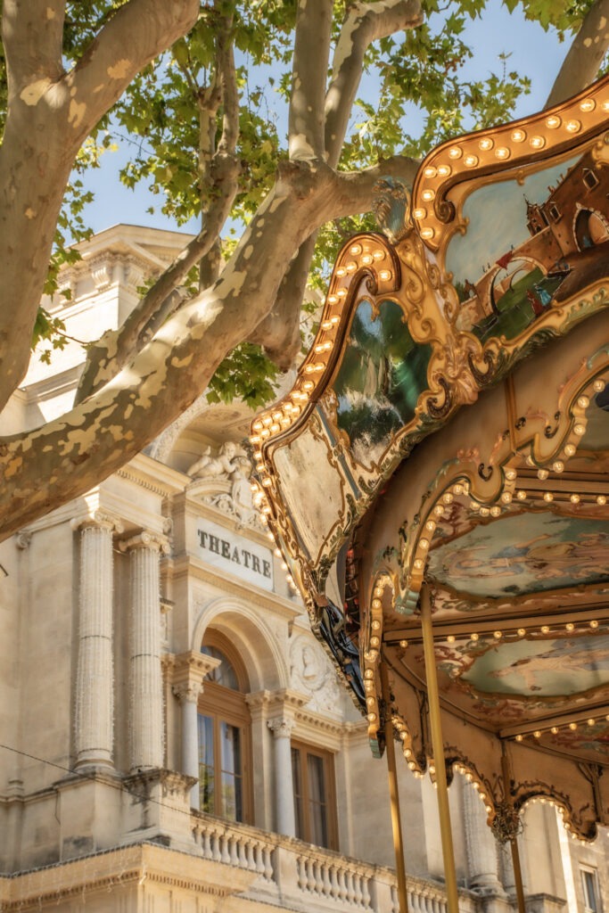 Ornate carousel beside the historic theatre building in central Avignon, France.