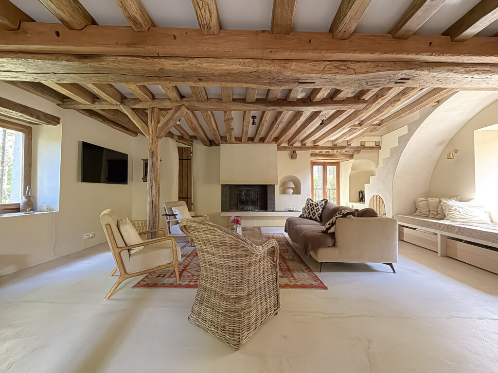 Living room at Moulin de Rochopt with original timber beams and fireplace