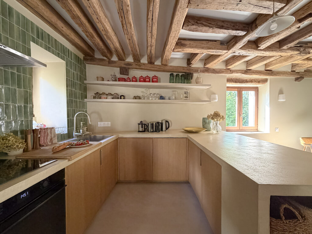 Kitchen at Moulin de Rochopt with green tile, natural wood and exposed beams