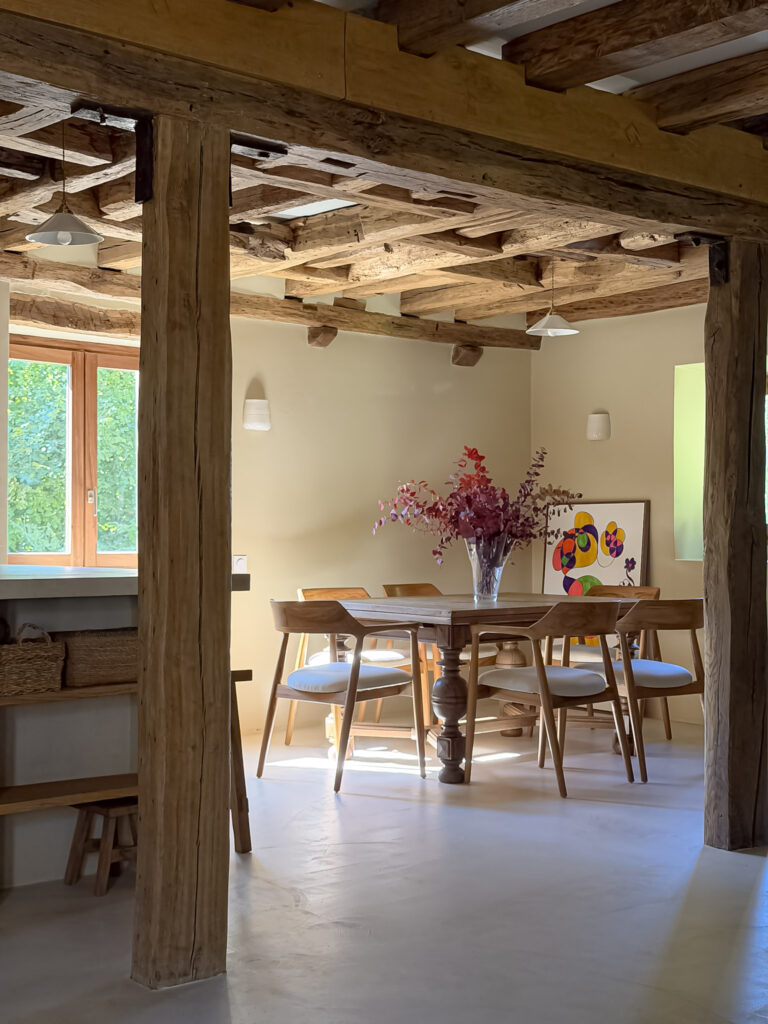 Dining room at Moulin de Rochopt with original timber structure and natural wood furnishings.