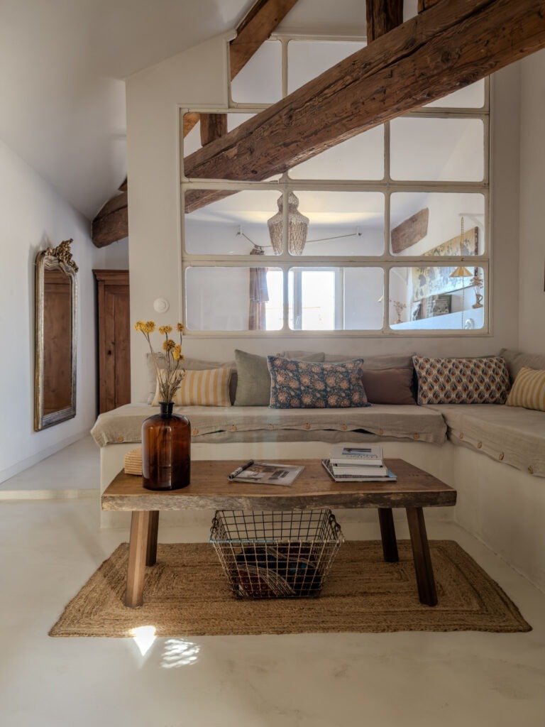 Living room at Le 40 by Maisons Clotilde with exposed wooden beams, built-in sofa and antique furnishings in L’Isle-sur-la-Sorgue.
