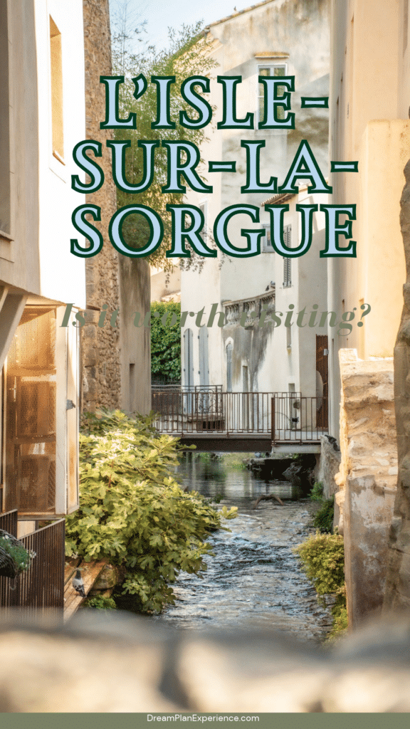 A narrow canal flowing between old stone and stucco buildings, with a small metal footbridge crossing the water. Text on photo reads is L'isle sur la Sorgue worth visiting