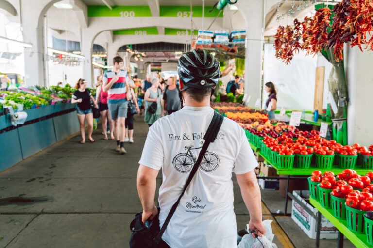 produce stands in jean talon market in montreal with man with bike helmet