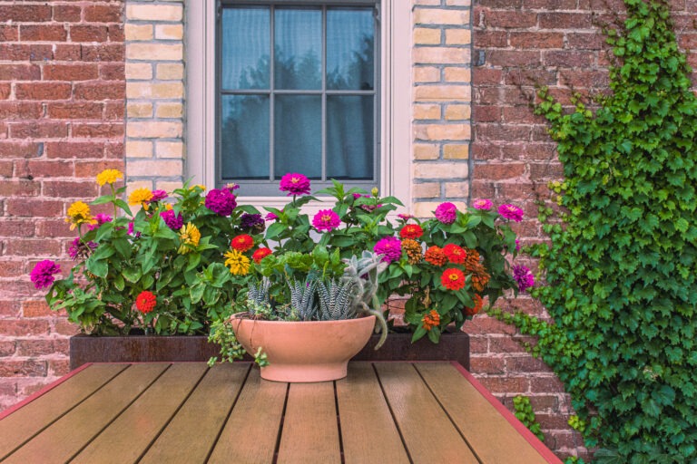 picnic table with flowers against red brick wall