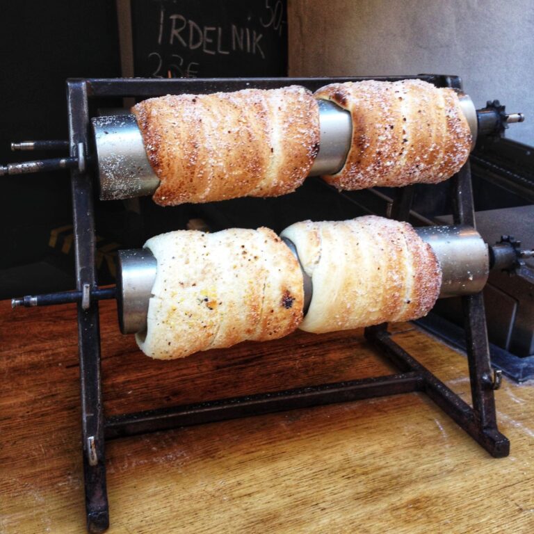 Trdelník is a kind of spit cake popular in Czech Republic. It is made from rolled dough that is wrapped around a stick, then grilled over an open firepit and topped with sugar and walnut mix.