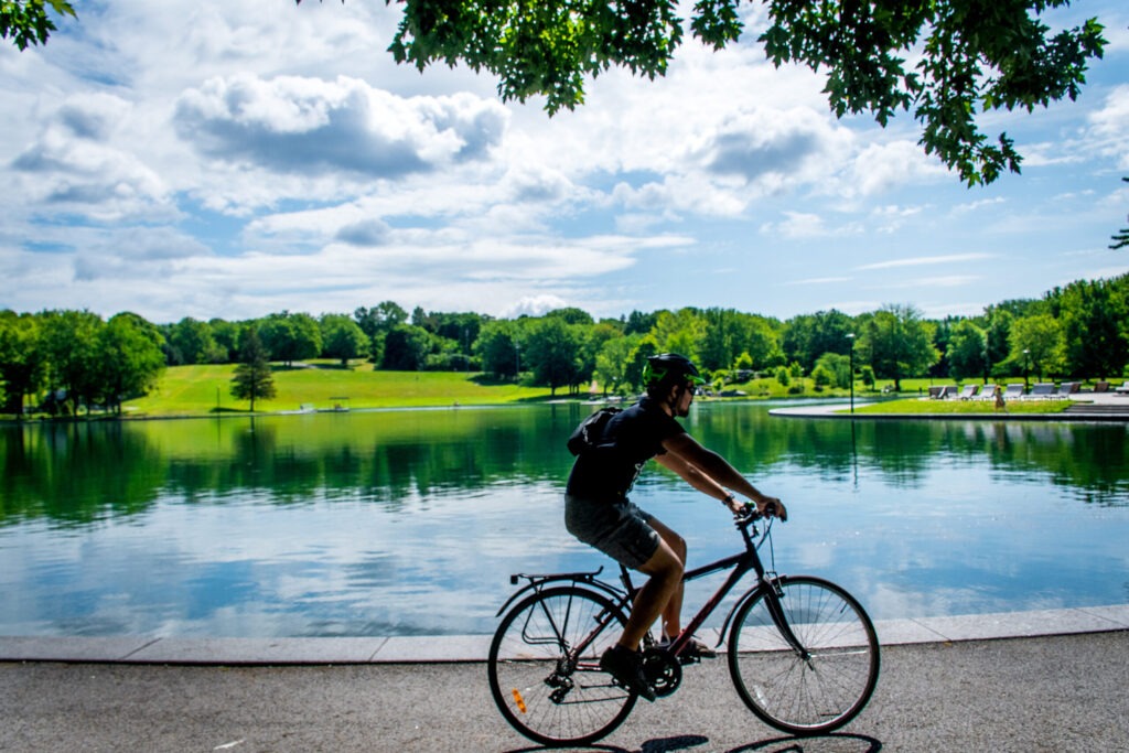 man on bike in front of lake in mont royal park in best neighbourhoods in montreal