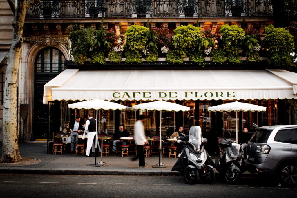 street with motorcycle in front of restaurants in paris 6th arrondissment with patrons sitting at tables