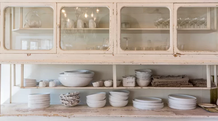 antique white pottery plates stacked on white cabinet in luberon provence