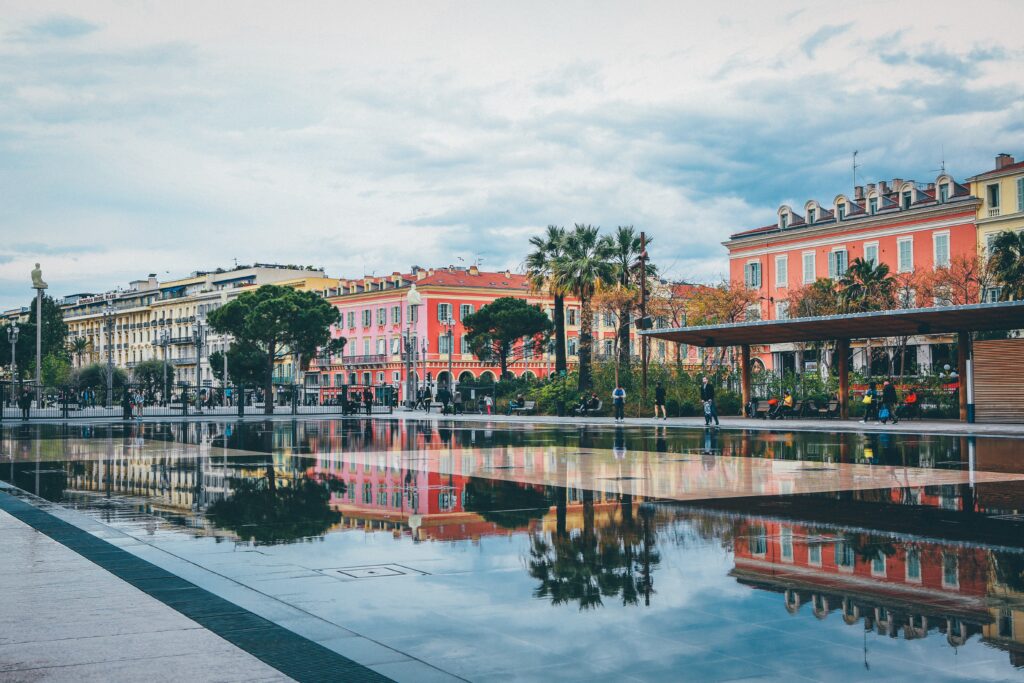 reflecting pond in square in nice france with colourful buildings