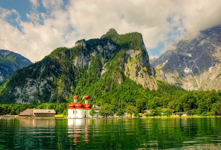 mountains on lake with white church and red dome roof