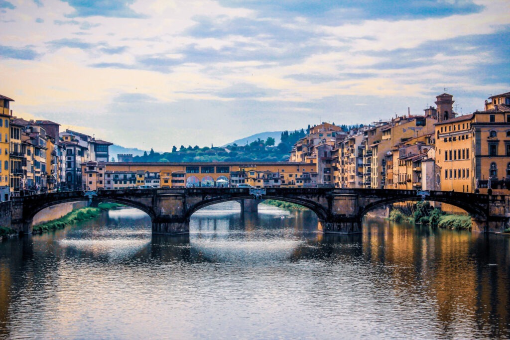 bridge over Arno river in Florence with buildings lining the riverbank