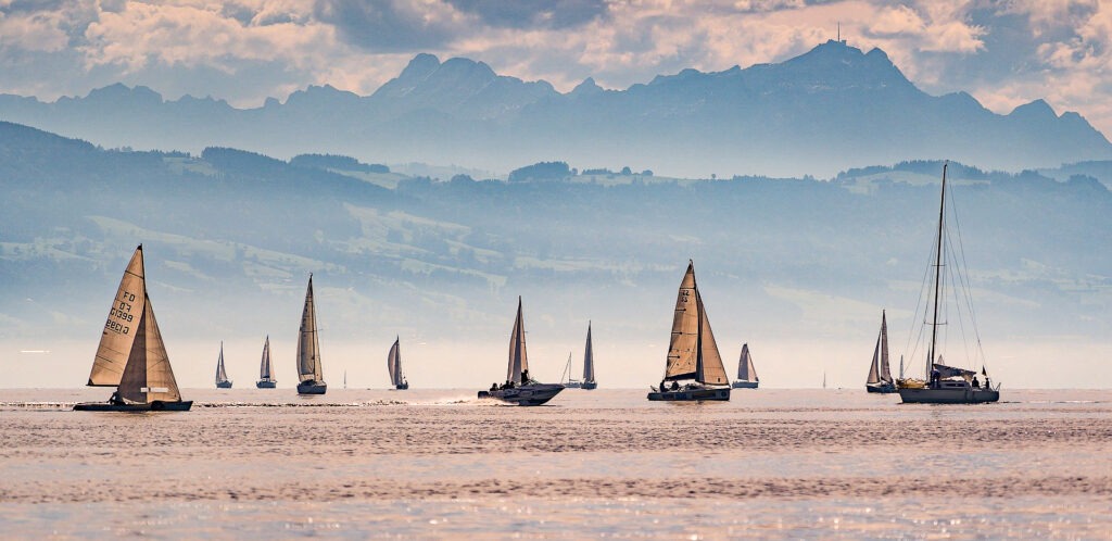 lake with sailboats and mountains in background in bodensee germany