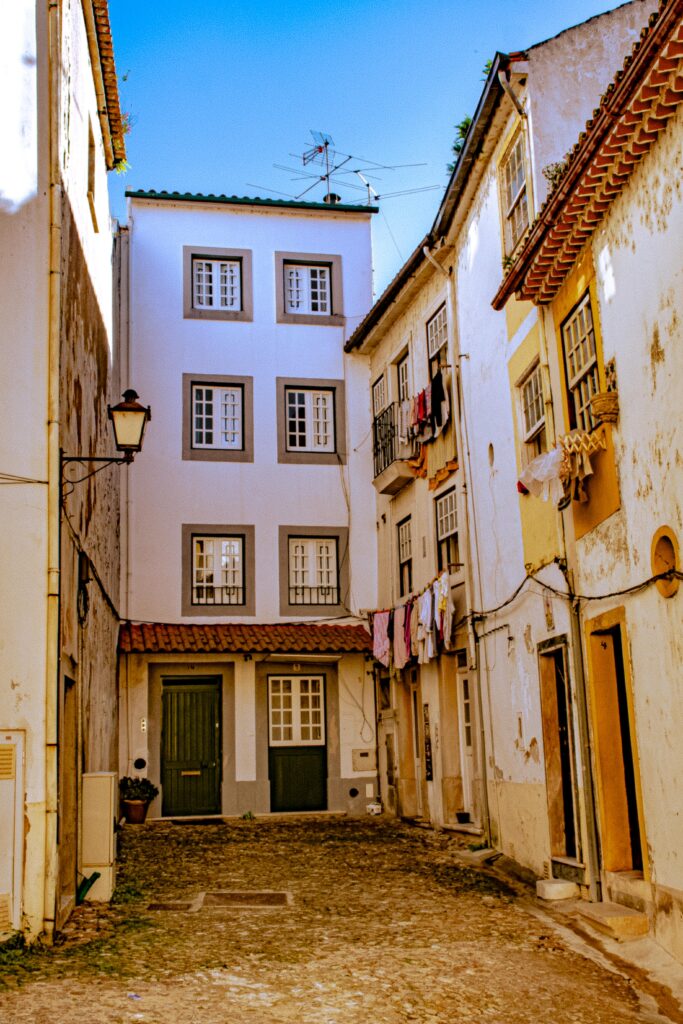 street with cobble stone tall buildings with laundry hanging in old town a must visit on day trip to coimbra