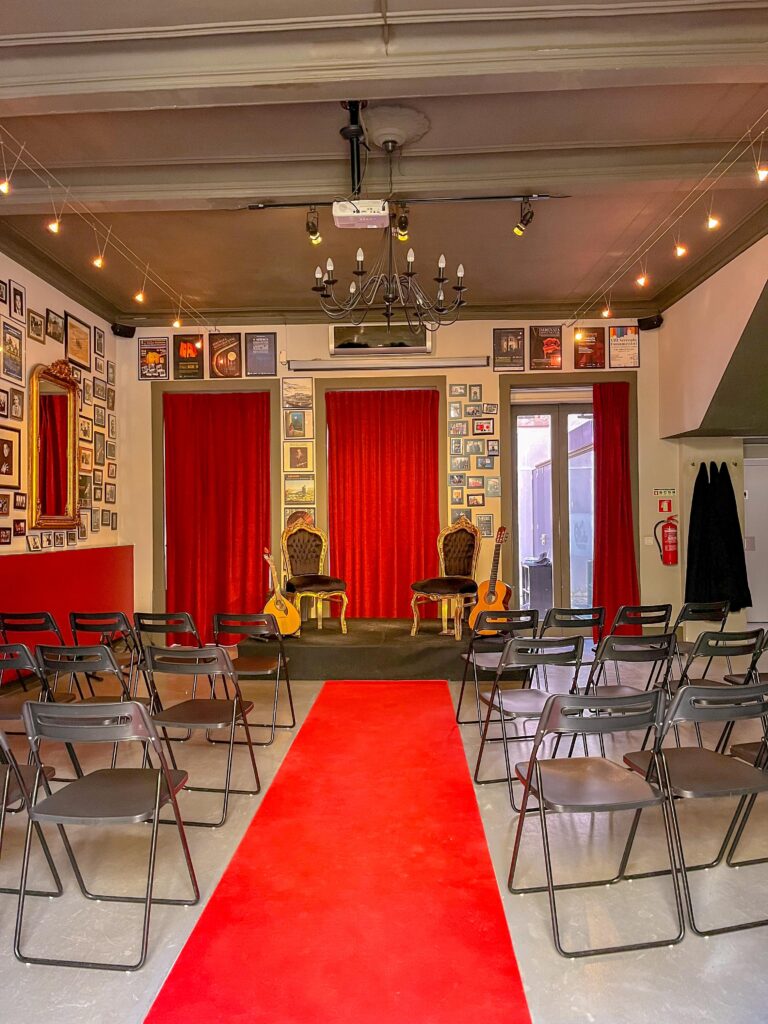 red carpet with chairs with stage and guitar for fado performance