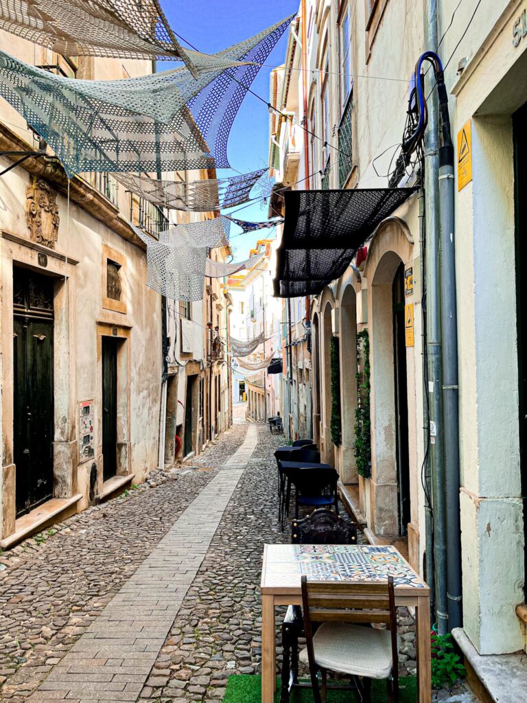 cobbled street with narrow laneway with sails over head