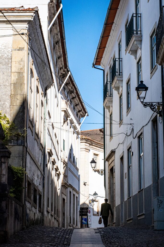 cobblestone street with tall buildings in historic centre in coimbra in portugal