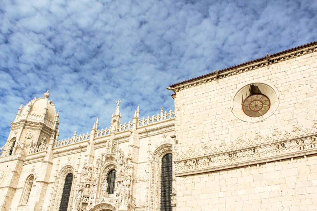visiting Jeronimos Monastery in Lisbon is limestone building with ornate details and tower