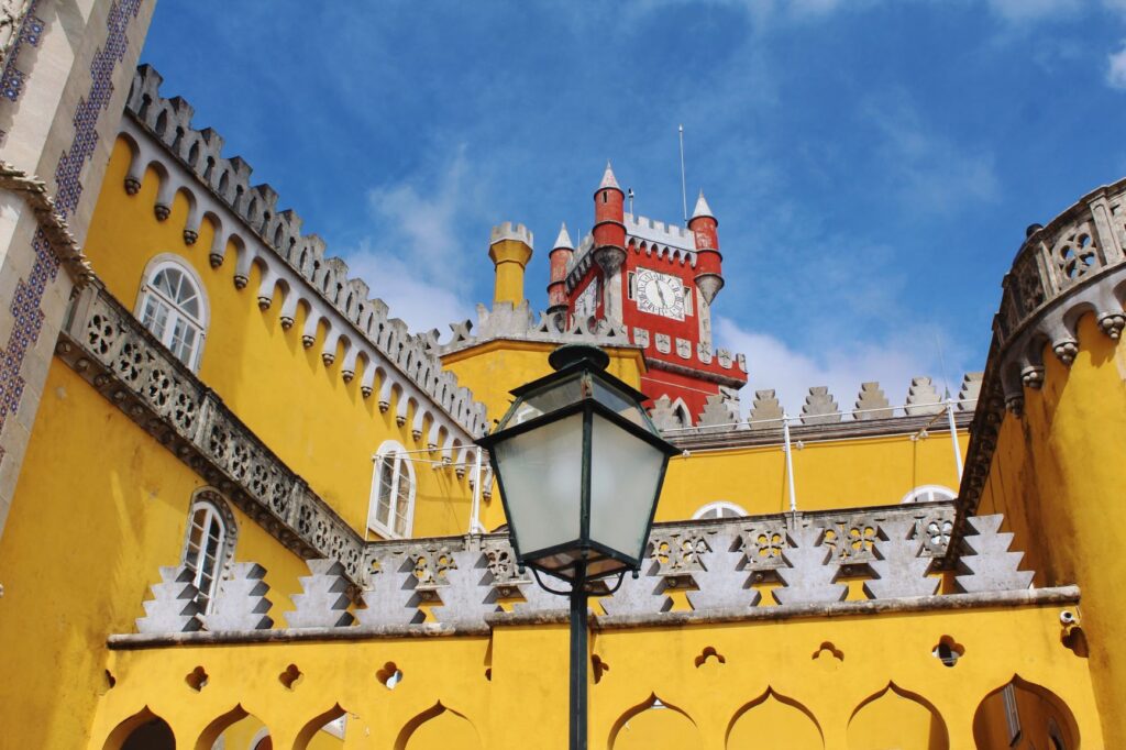 yellow palace with red clock tower at tips visitin Pena Palace Sintra