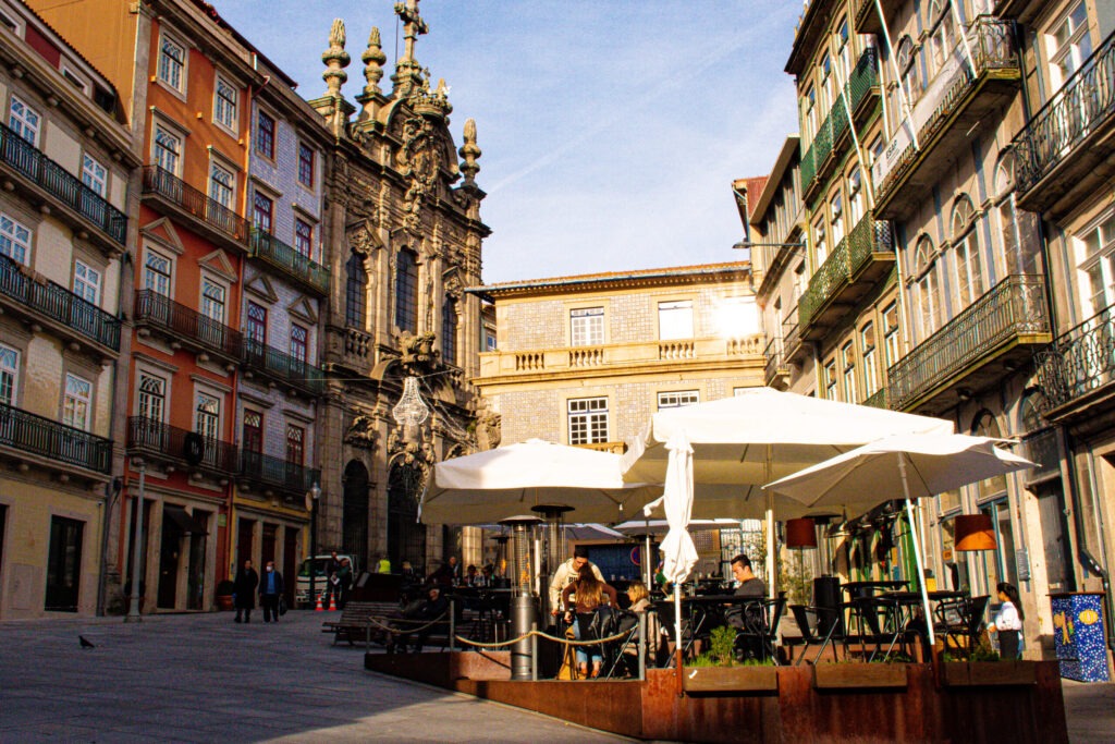 street in porto with restaurants and umbrellas surrounded by colourful buildings