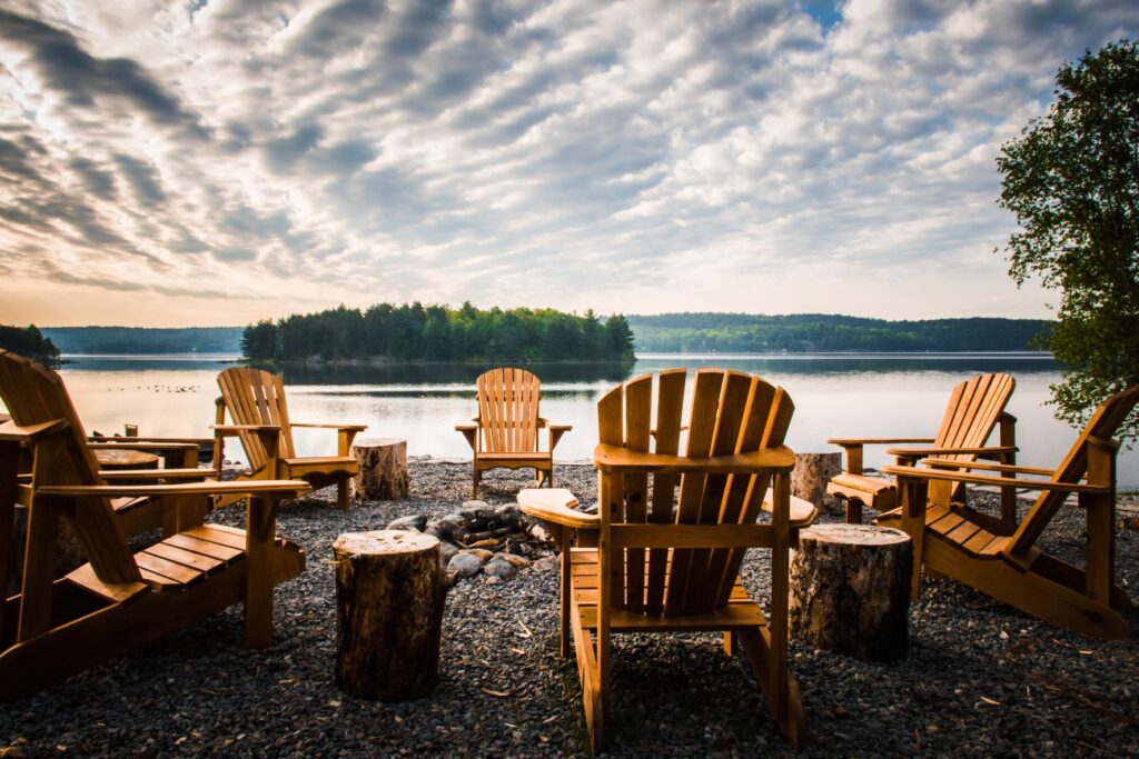 fire pit in front of lake with chairs