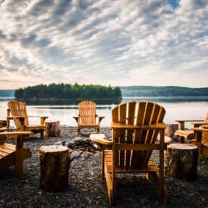 fire pit in front of lake with chairs