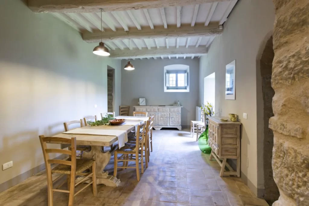 stone floor, beamed ceiling, table and chairs for dining in one the the vacation rentals in cortona italy