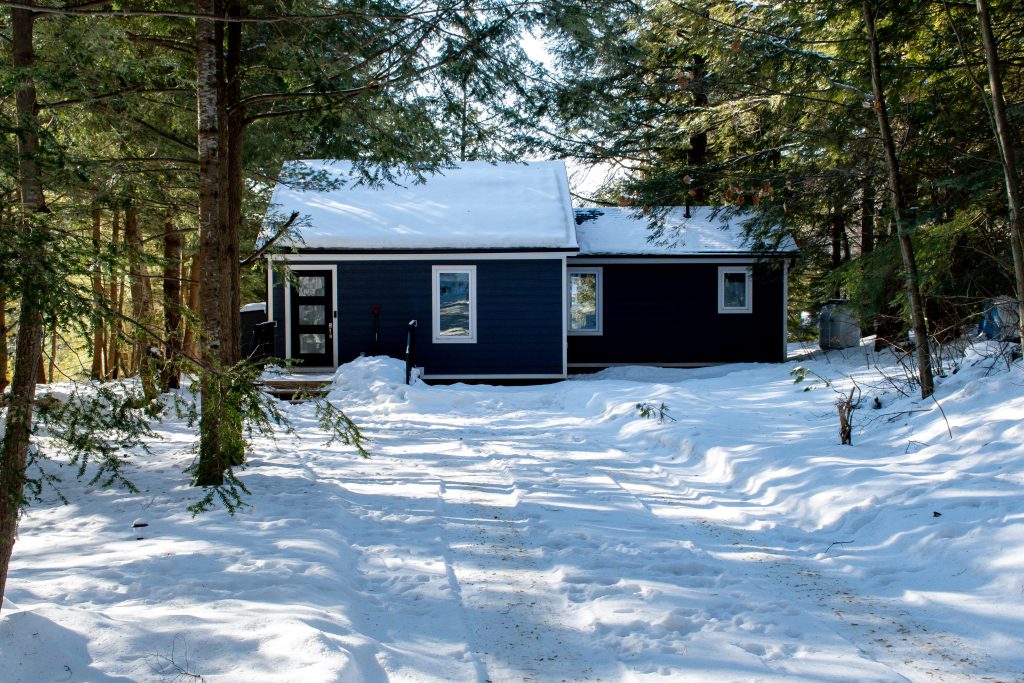 dark gray Scandinavian Muskoka cottage in the winter with trees and snow