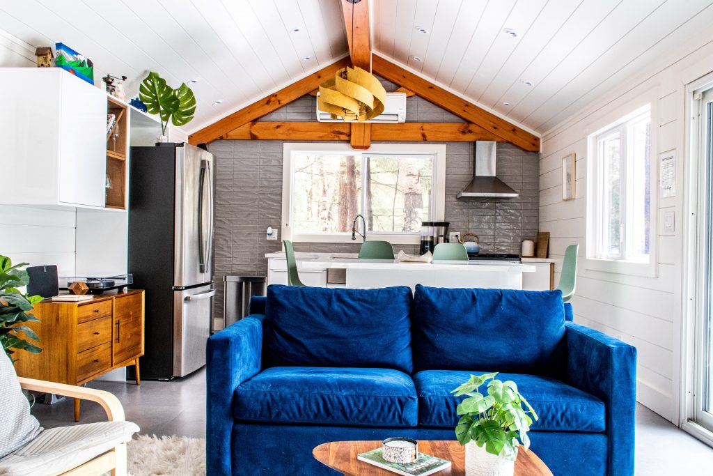 blue sofa, kitchen island, window with fridge, white walls at scandinavian muskoka cottage 