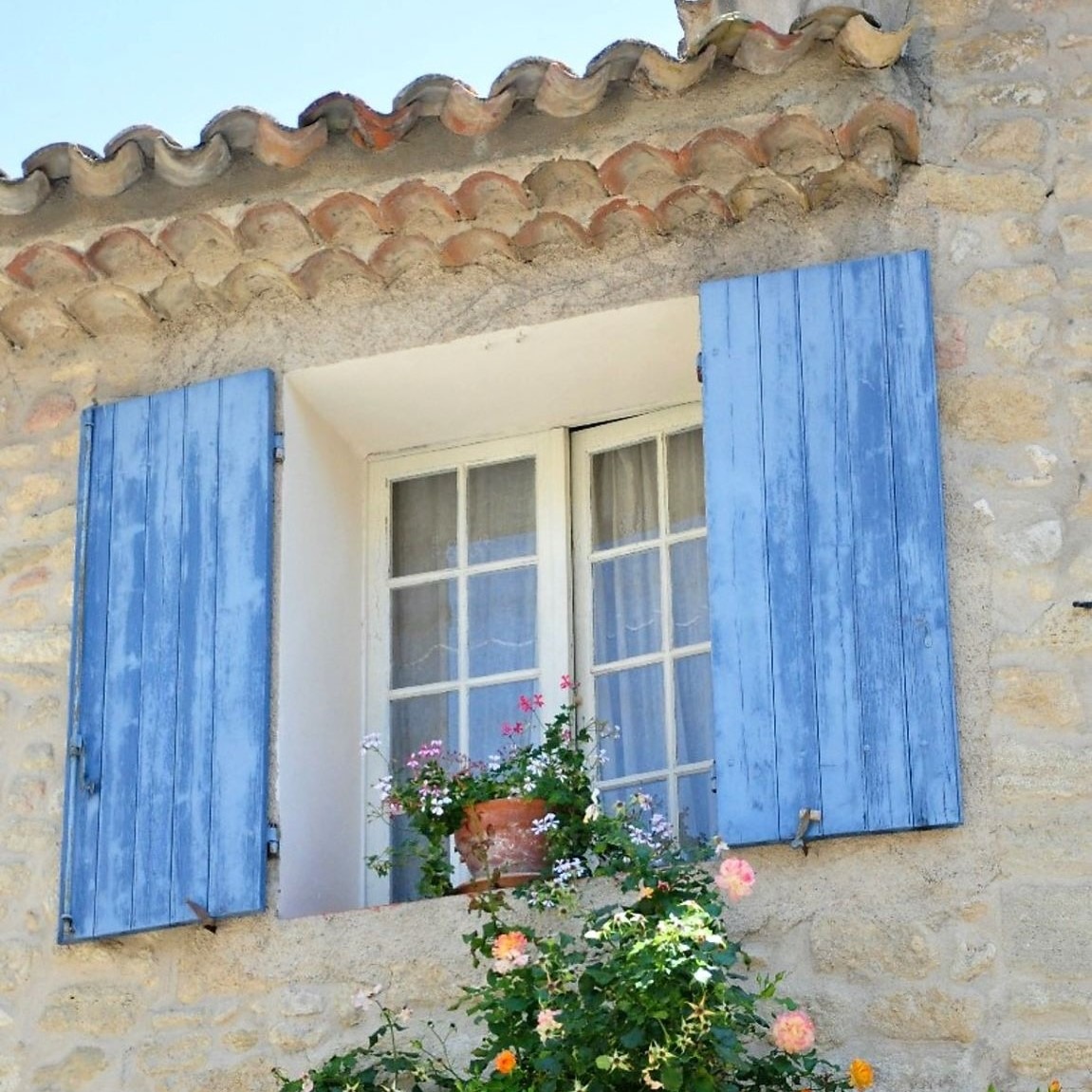 stone building with blue shutters and flowers